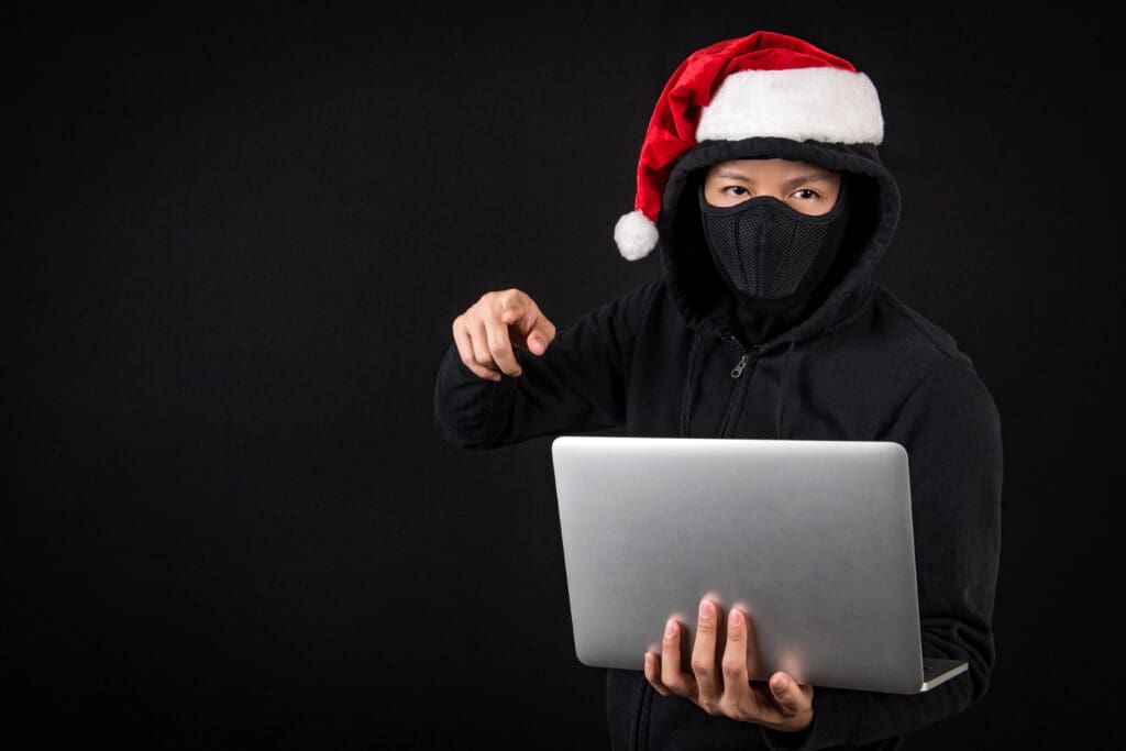 criminal holding computer to illustrate scams during the holidays
