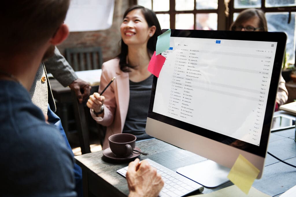 Coworkers-discuss-their-plans-for-the-work-day-with-email-inbox-open-on-their-screen
