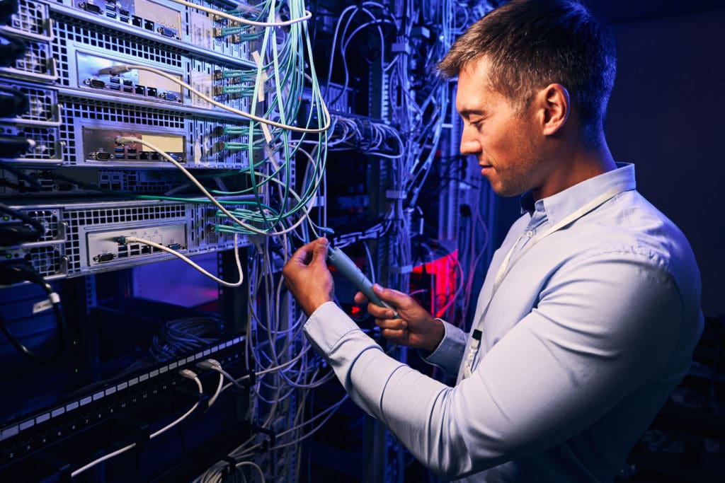 IT Technician working in computer room while looking for IT Infrastructure Holes with KT Connections.