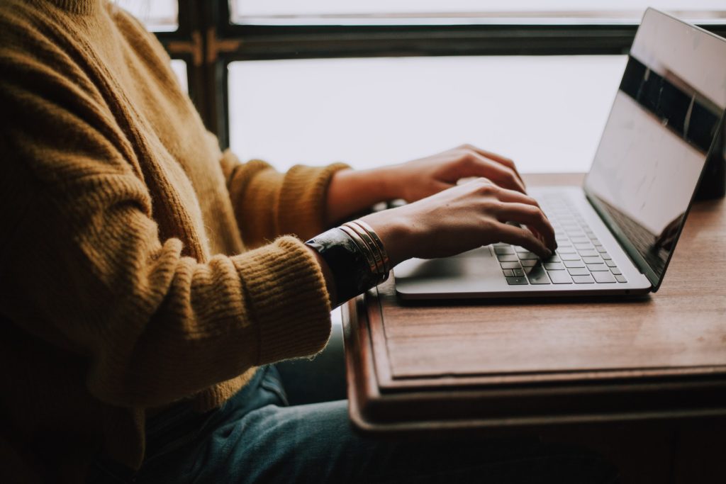 woman's hands typing on laptop